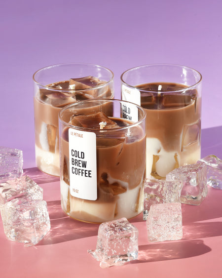 A 15 oz layered candle in a clear glass jar: deep espresso-brown coffee soy wax base, topped with creamy milk-white wax and translucent gel "ice cubes," evoking a perfectly chilled iced coffee latte.